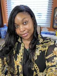 a woman in a black and gold shirt sitting at a desk